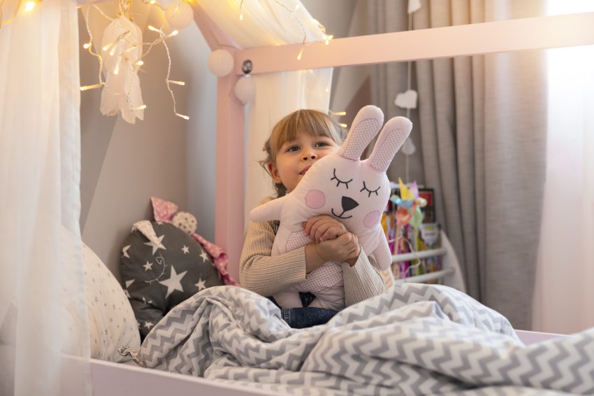 Łóżka domek dla dziecka – dziewczynka z pluszakiem bawiąca się w swoim pokoju