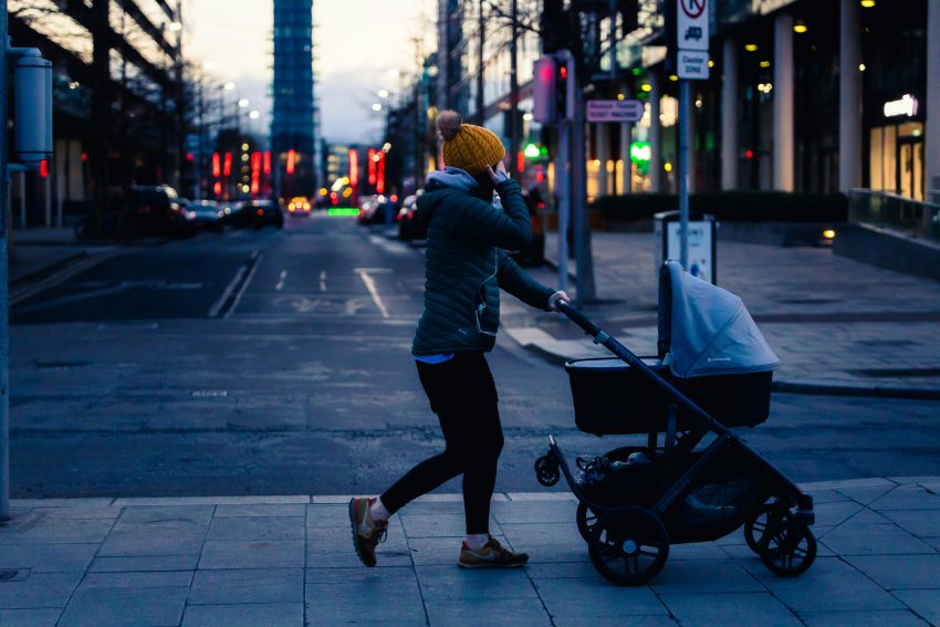 zdjęcie dziecka w wózku i mamy spacerujących po miastu